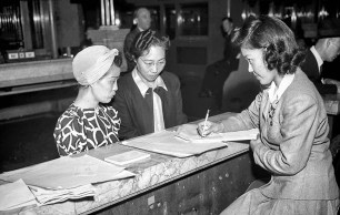Mar. 30, 1942: Two Japanese women get information from Japanese clerk regarding plans for their removal. Photo was published Mar. 31, 1942 with story announing the removal of all Japanese from the Los Angeles Harbor area.